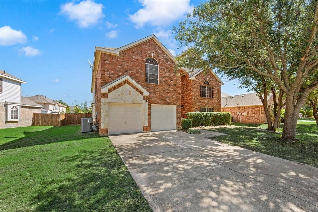 Beautiful curb appeal shines with a spacious driveway, two-car garage & a welcoming front yard shaded by mature trees.