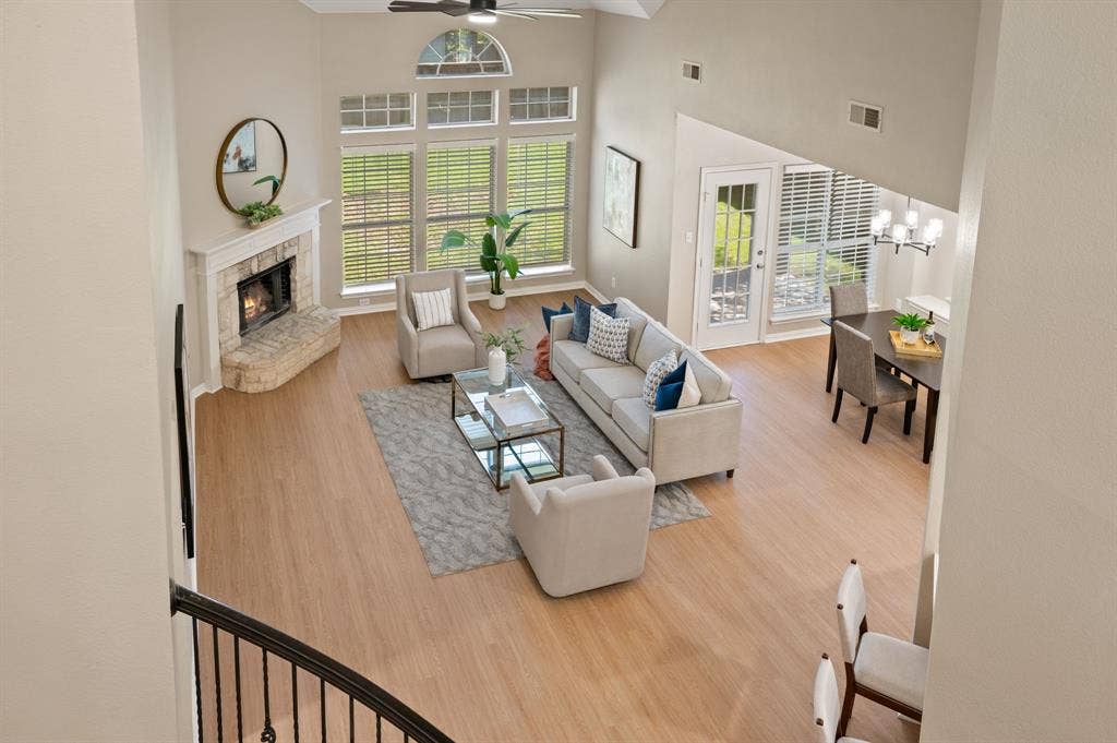 A view from above showcases the living room’s soaring ceilings, dramatic windows & cozy corner fireplace.