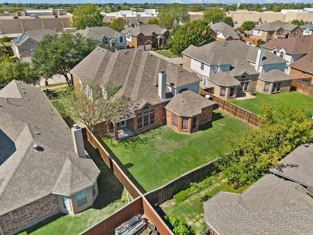 This aerial view highlights the home’s spacious backyard, fenced outdoor space & attractive brick exterior.