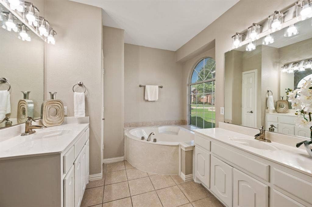 Two spacious vanities offer room to spread out, while an arched window brings beautiful natural light to the soaking tub.