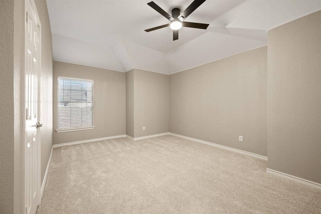 New carpet, a ceiling fan & a walk in closet create a welcoming setting in this spacious secondary bedroom.