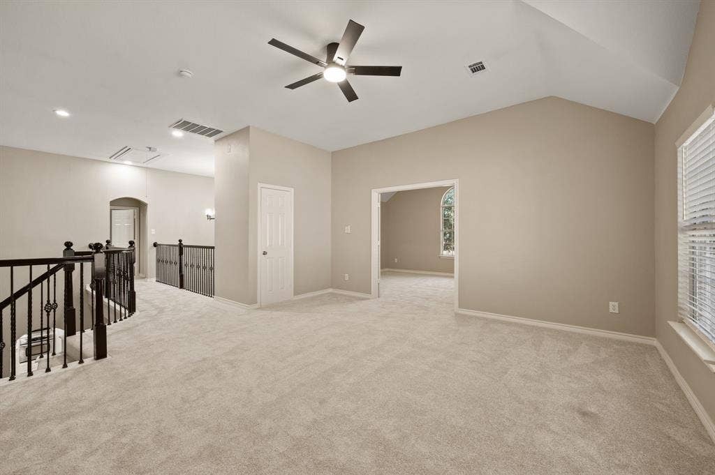 Ready for game nights or a cozy lounge, the open upstairs living area offers flexible space beside the decorative iron railing.