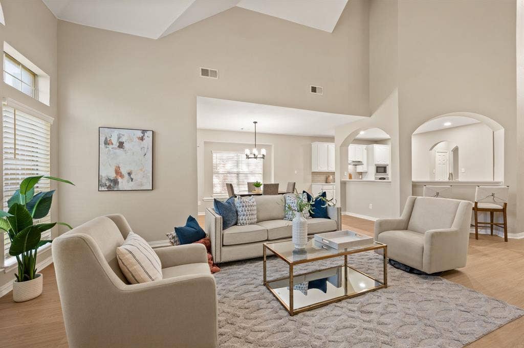 Enjoy room to gather in this light-filled living space, with tall ceilings, warm flooring & arched openings toward the kitchen.