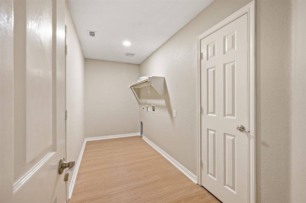 A separate laundry room offers dedicated space for household chores, with appliance connections & a handy shelf with a hanging rod.