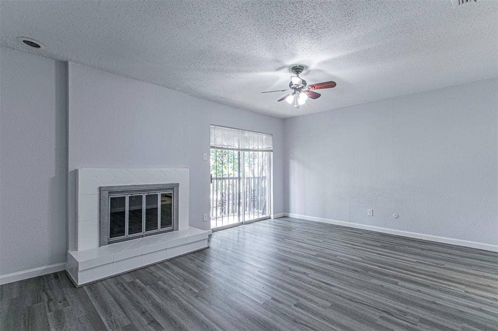 9326 Emberglow Lane, Dallas, TX 75243 Bedroom 3 - Unfurnished living room featuring a tile fireplace, dark wood finished floors, a textured ceiling, and ceiling fan