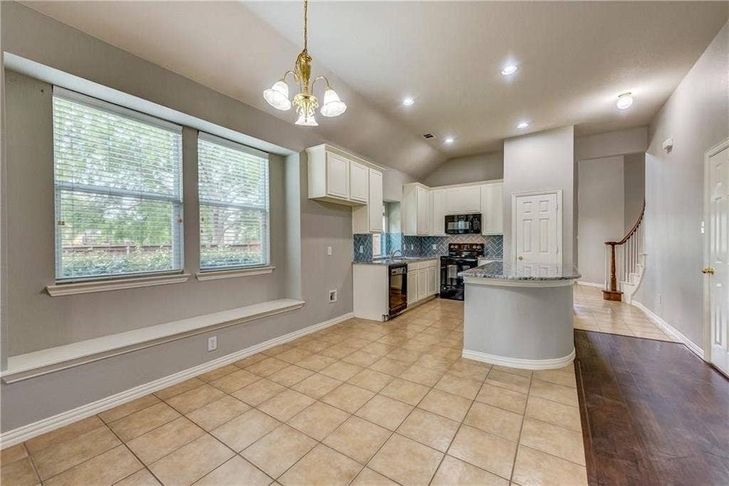 2300 Reston Drive, McKinney, TX 75072 Kitchen featuring light tile floors, backsplash, white cabinetry, black appliances, and vaulted ceiling