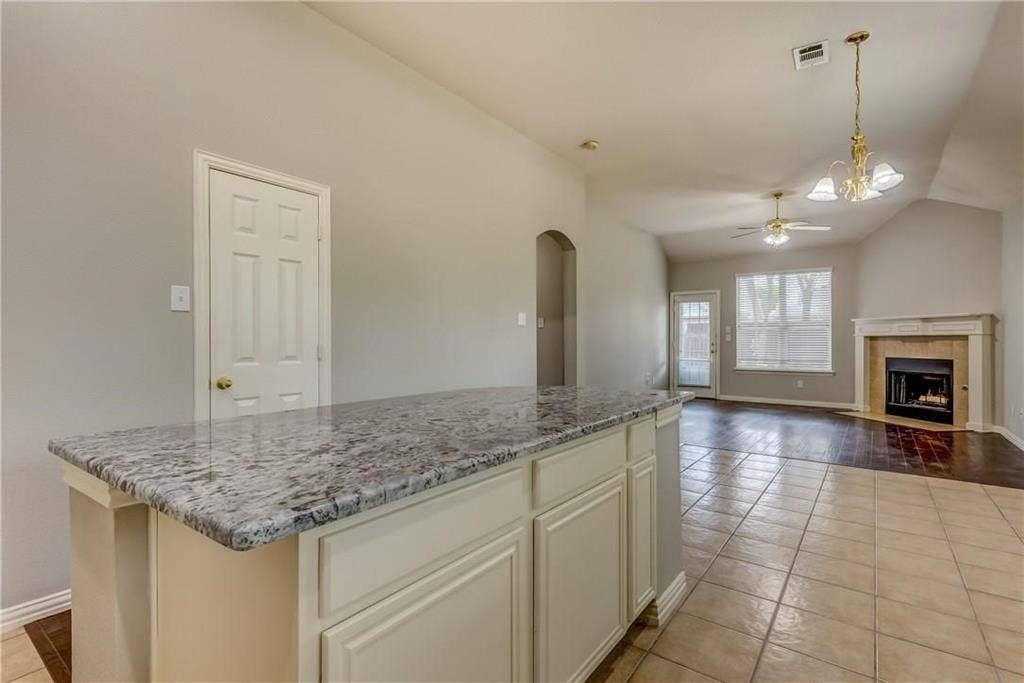 2300 Reston Drive, McKinney, TX 75072 Kitchen with ceiling fan with notable chandelier, a tile fireplace, pendant lighting, a center island, and light tile floors