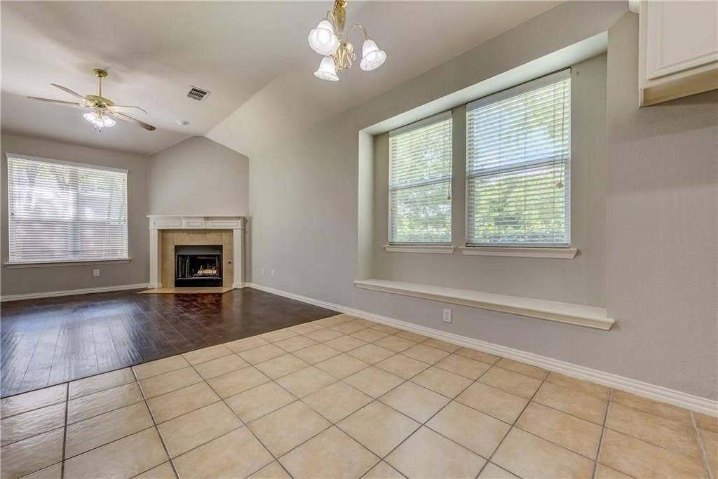 2300 Reston Drive, McKinney, TX 75072 Unfurnished living room with vaulted ceiling, light hardwood / wood-style floors, ceiling fan with notable chandelier, and a tile fireplace