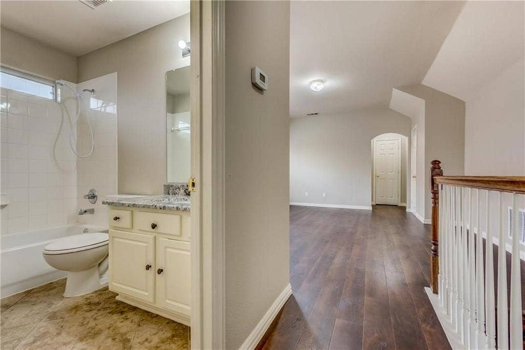 2300 Reston Drive, McKinney, TX 75072 Full bathroom with tiled shower / bath, vaulted ceiling, toilet, wood-type flooring, and vanity