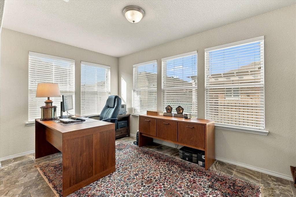 Room featuring tile flooring, neutral wall paint, and five windows with horizontal blinds