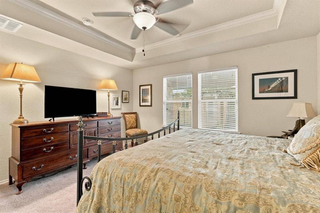 Tray ceiling featuring a central ceiling fan with integrated lighting and two windows with horizontal blinds