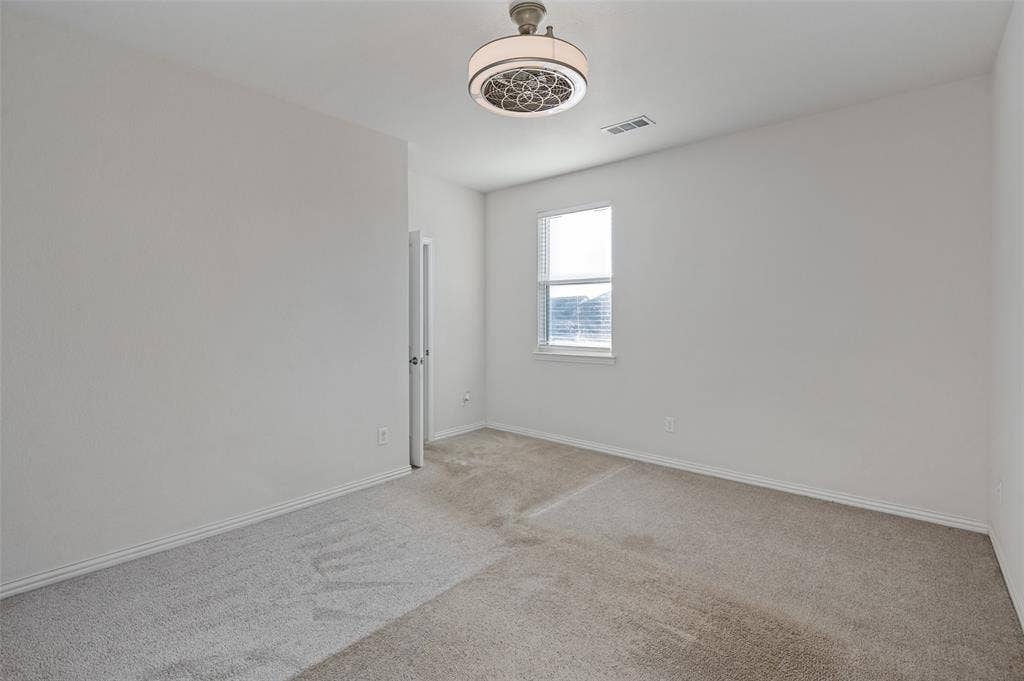 Neutral wall finishes, plush carpeting, single-pane window, and a drum-style ceiling fan with integrated lighting