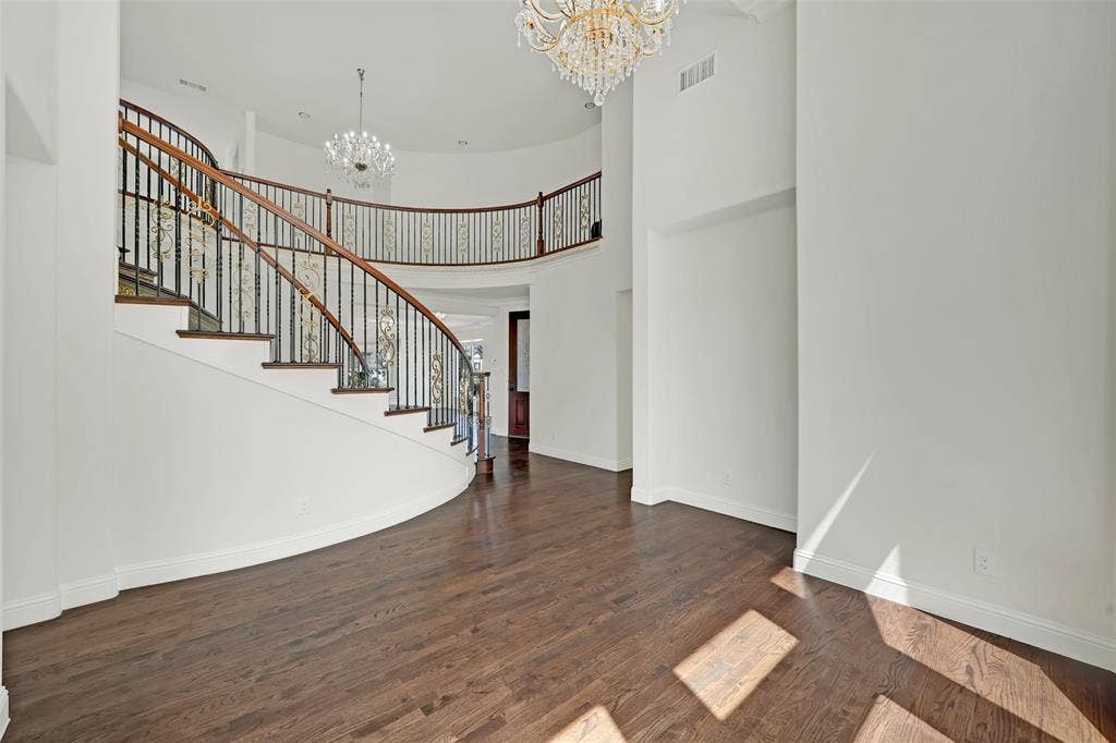 302 Torch Lily Lane, Wylie, TX 75098 Grand two-story entry with a curved staircase, wrought iron balusters, wood-finish flooring, and two chandelier light fixtures