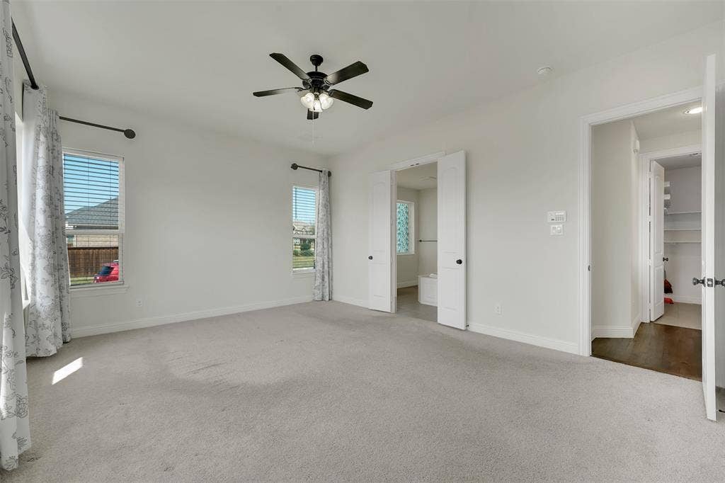 302 Torch Lily Lane, Wylie, TX 75098 Spacious room featuring light-colored carpeting, two windows with blinds, and a ceiling fan with integrated lighting