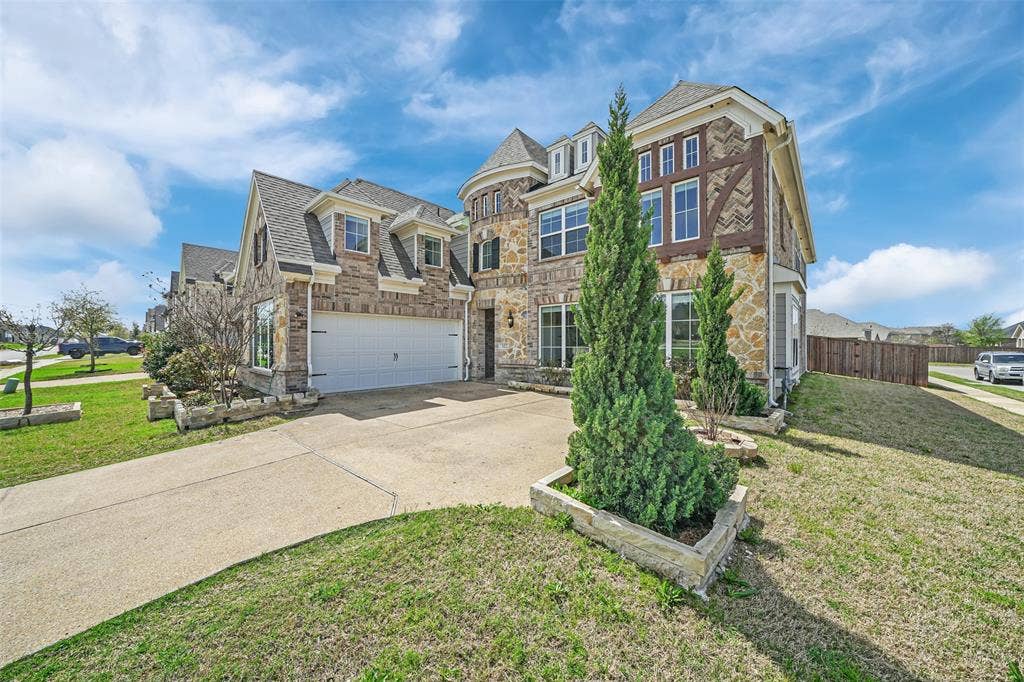 302 Torch Lily Lane, Wylie, TX 75098 Stone and siding exterior with decorative wood accents, multi-pane windows, dormer windows, and an attached two-car garage