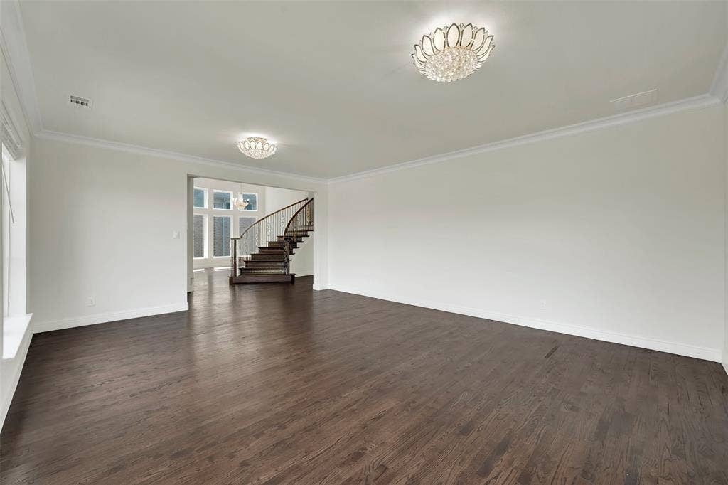 302 Torch Lily Lane, Wylie, TX 75098 Hardwood flooring throughout, crown molding, two flush-mount crystal light fixtures, and a curved staircase with wood treads and a dark wood handrail