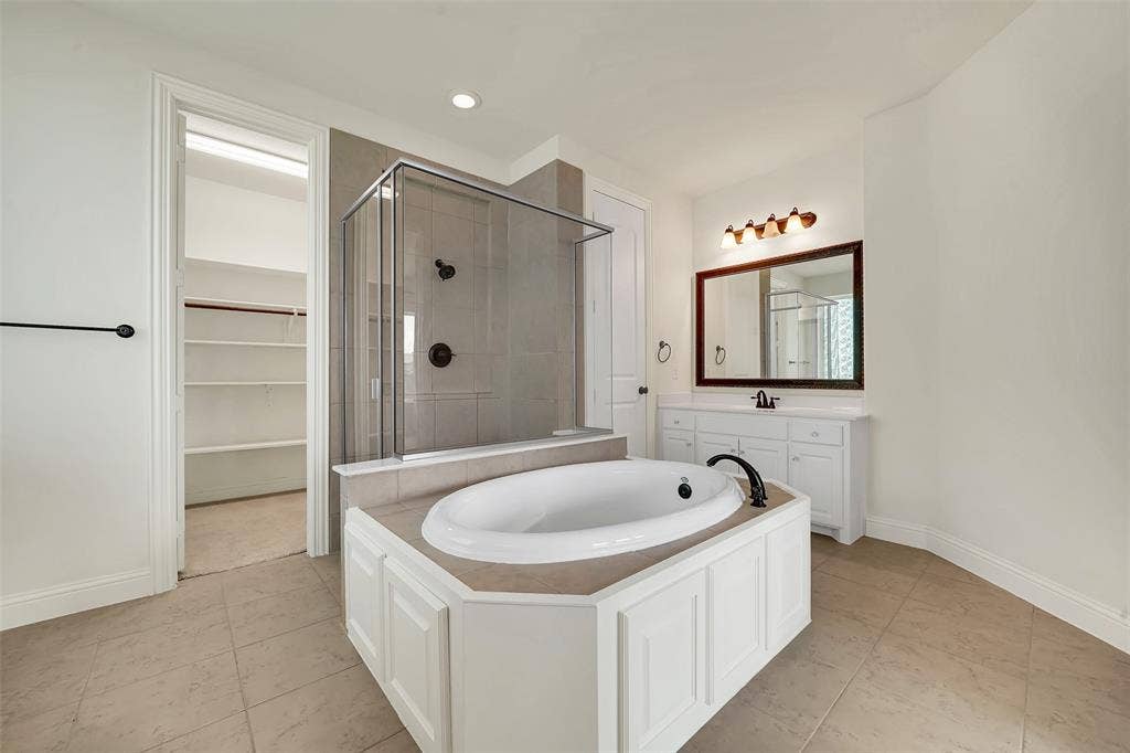 302 Torch Lily Lane, Wylie, TX 75098 Soaking tub with a tiled surround, glass-enclosed shower, white vanity with a dark countertop, and tiled flooring