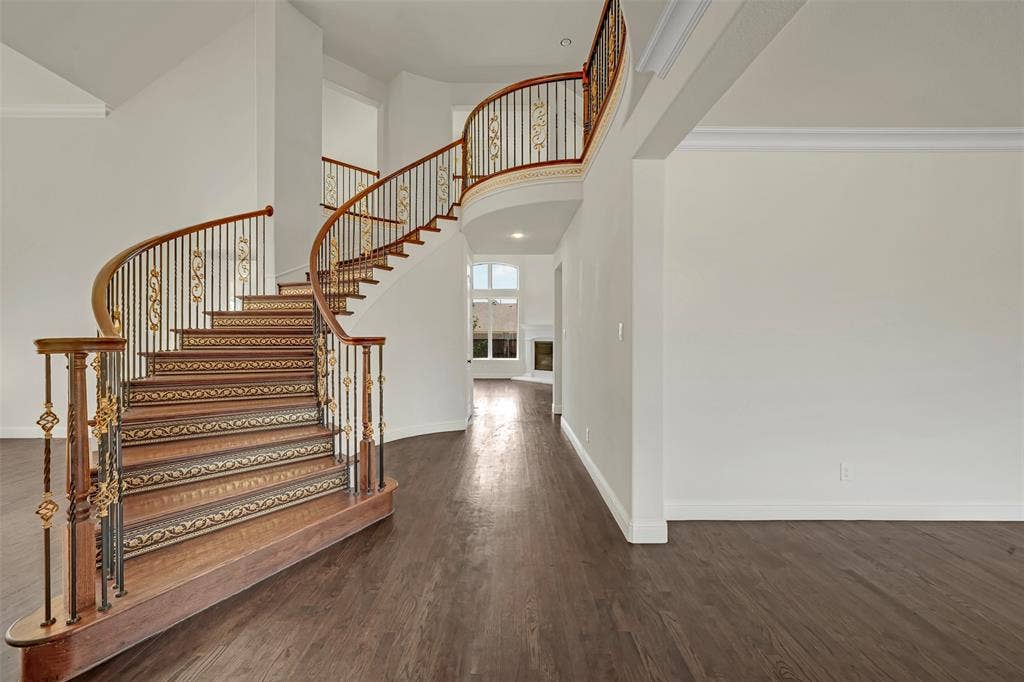 302 Torch Lily Lane, Wylie, TX 75098 Curved staircase with wrought iron balusters and ornate detailing, wood-finish flooring, crown molding, and high ceilings
