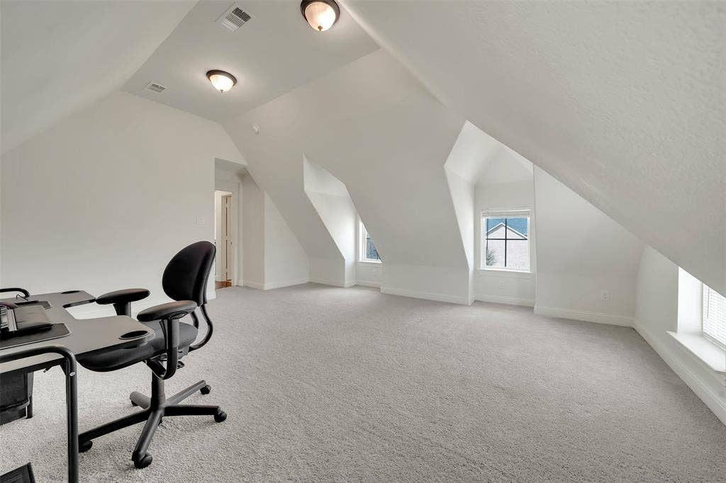 302 Torch Lily Lane, Wylie, TX 75098 Spacious attic room featuring sloped ceilings, recessed dormer windows with blinds, light-toned carpeting, and flush-mount ceiling lights
