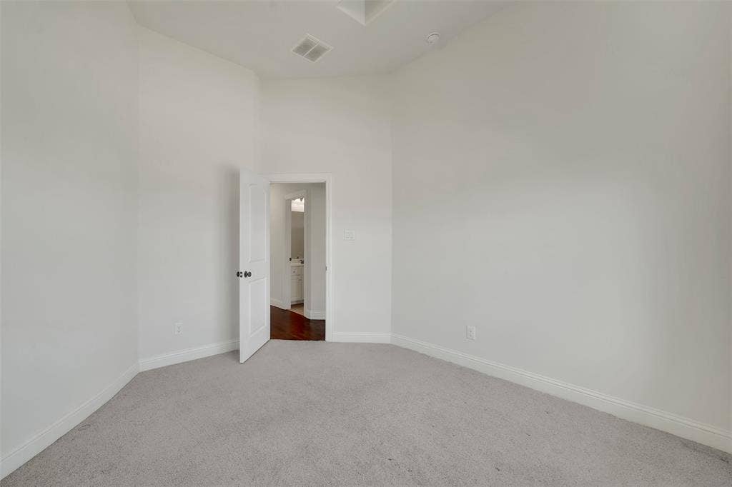 302 Torch Lily Lane, Wylie, TX 75098 Vaulted ceiling, light neutral wall color, plush carpet flooring, white interior door, and dark wood-finish flooring visible through doorway