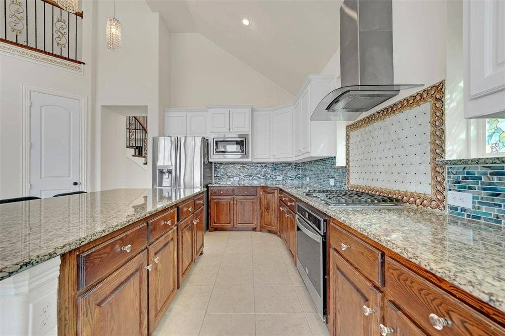 302 Torch Lily Lane, Wylie, TX 75098 Kitchen featuring granite countertops, wood-finish lower cabinetry, white upper cabinetry, stainless steel appliances, and a mosaic tile backsplash
