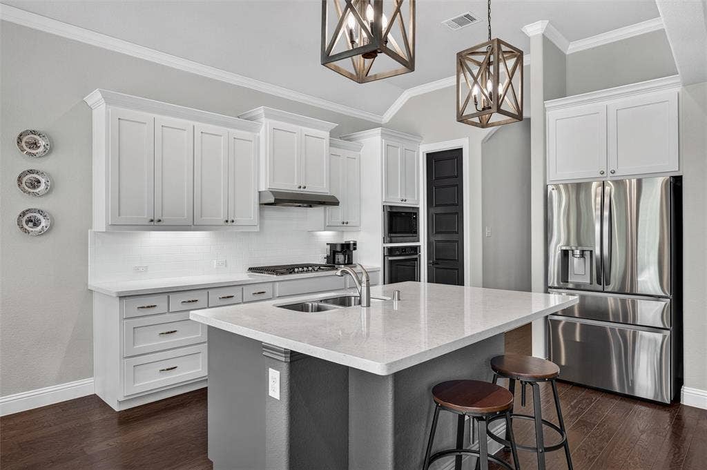 7601 Calhoun Cove, McKinney, TX 75071 Kitchen featuring white shaker cabinetry, stainless steel appliances, a center island with countertop seating, a subway tile backsplash, and wood-finish flooring