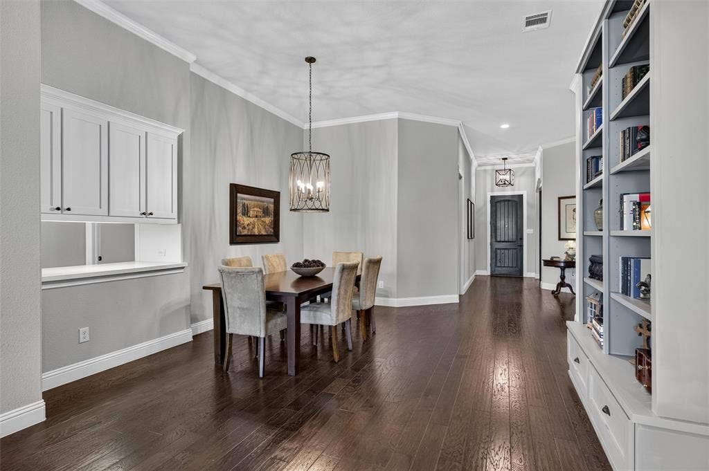 7601 Calhoun Cove, McKinney, TX 75071 Wood-finish flooring throughout, featuring a built-in buffet with upper cabinetry, a built-in bookcase with lower drawers, and crown molding