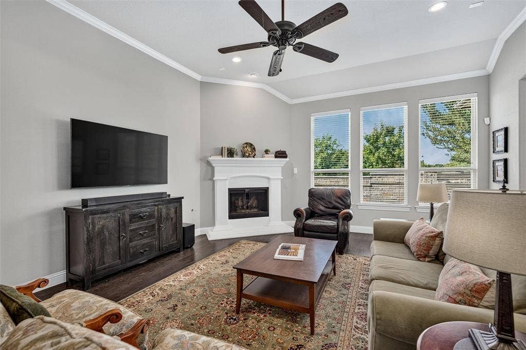 7601 Calhoun Cove, McKinney, TX 75071 Living area featuring wood-finish flooring, a white mantel fireplace, and three tall windows
