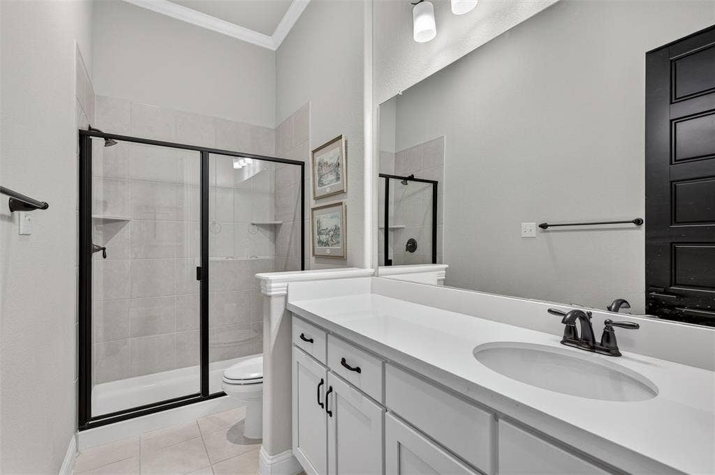 7601 Calhoun Cove, McKinney, TX 75071 White vanity with multiple storage cabinets, an integrated sink, and a dark bronze faucet