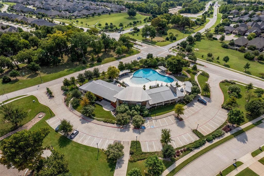 7601 Calhoun Cove, McKinney, TX 75071 Community clubhouse featuring a large swimming pool, expansive parking, and surrounding green spaces with mature trees