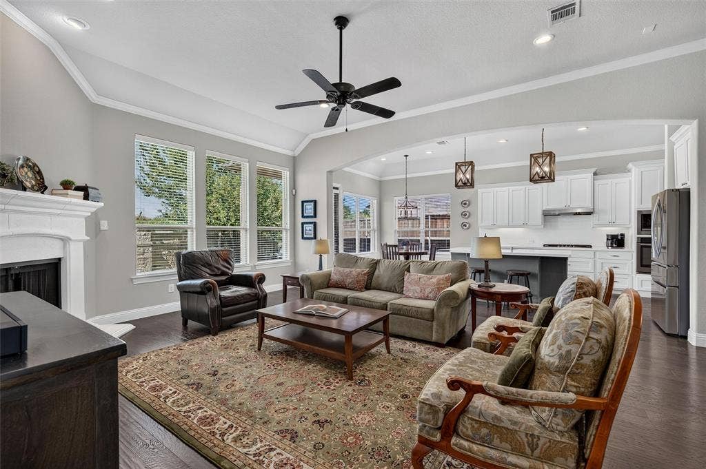 7601 Calhoun Cove, McKinney, TX 75071 Vaulted ceilings, wood-finish flooring, white cabinetry, integrated stainless steel appliances, and a built-in fireplace with a mantel
