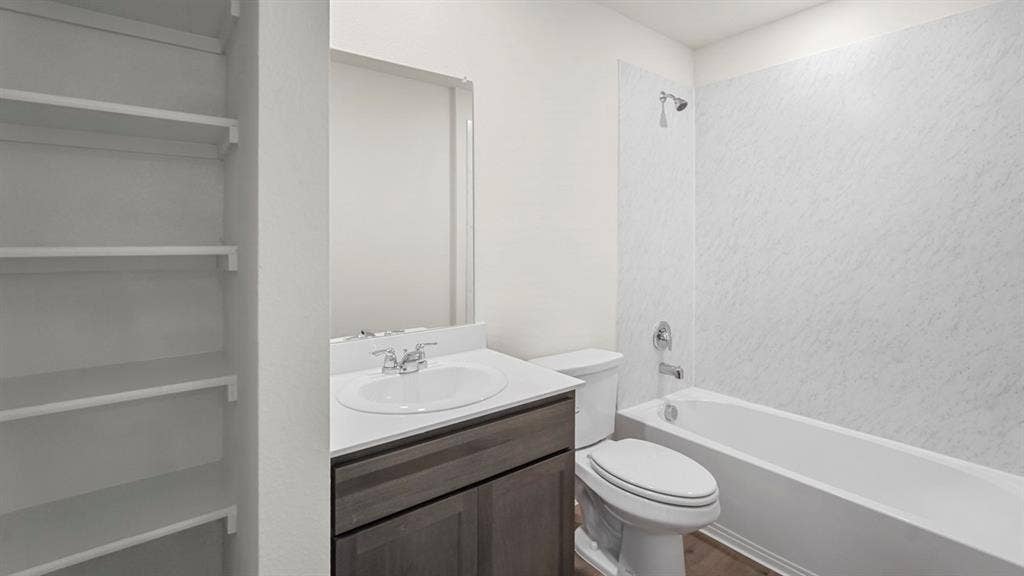 1671 Blaire Drive, Tyler, TX 75702 Built-in shelving, vanity with a white countertop, undermount sink, chrome faucet, and a combination tub/shower with textured surround