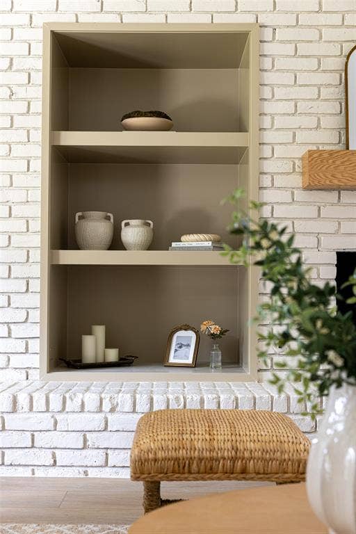 Creatively integrated built-in shelving with a sophisticated neutral finish, adding architectural character and an elegant display space beside the white brick fireplace.
