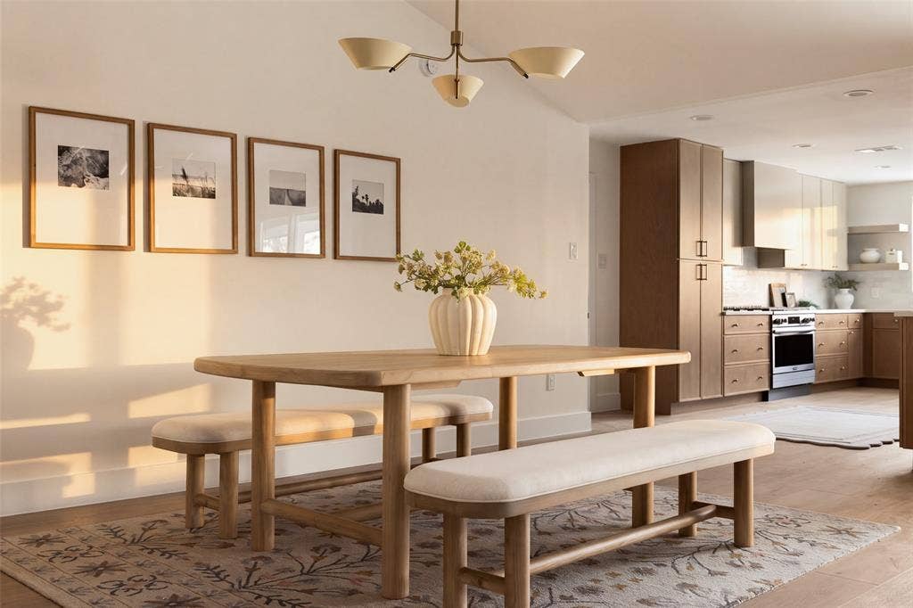 Open living and dining areas with vaulted ceilings, wood-like flooring, modern lighting, flowing into the updated kitchen.