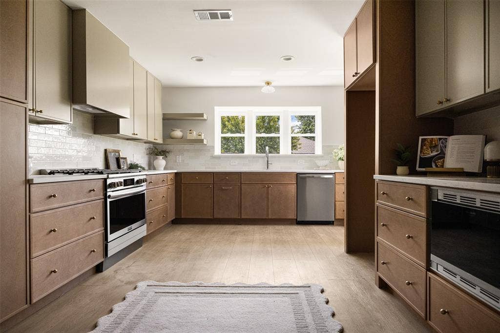 Expansive, open kitchen featuring a generous layout, elegant finishes, brass accents, stainless steel appliances, and abundant storage.