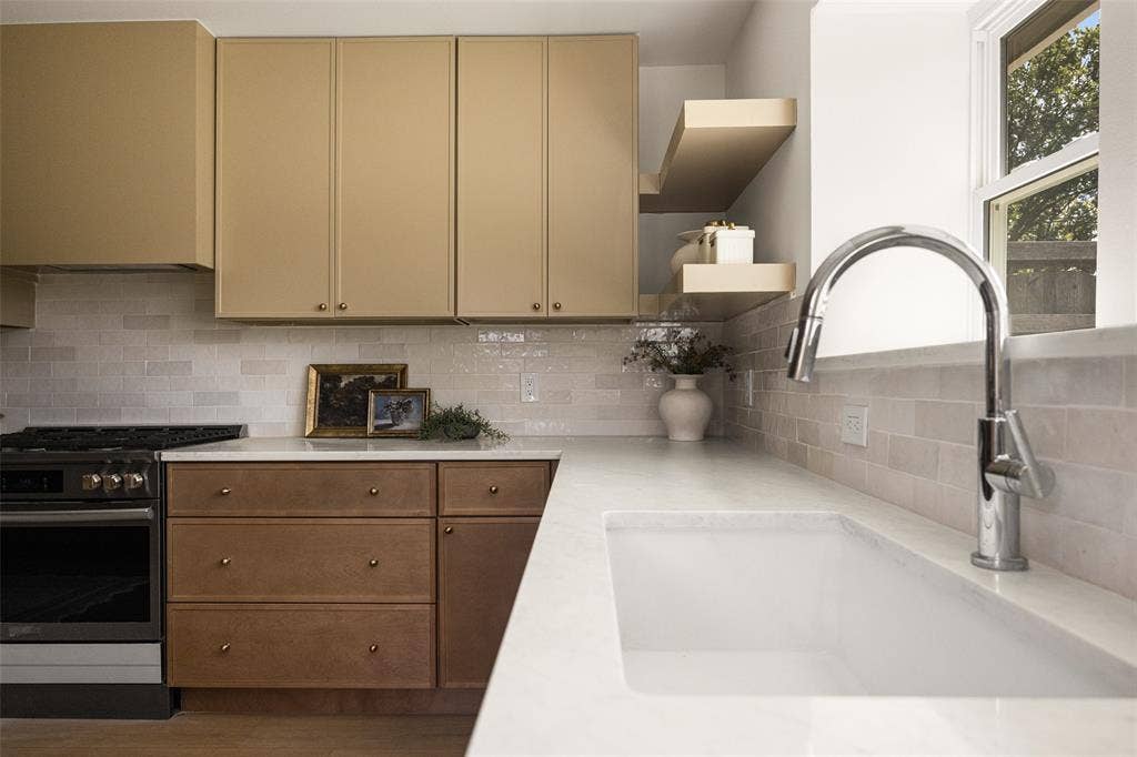 Sophisticated, designer-inspired kitchen featuring rich wood cabinetry, elegant stone-look countertops, artisan-style tile backsplash, warm brass accents, stainless steel appliances, and abundant natural light.