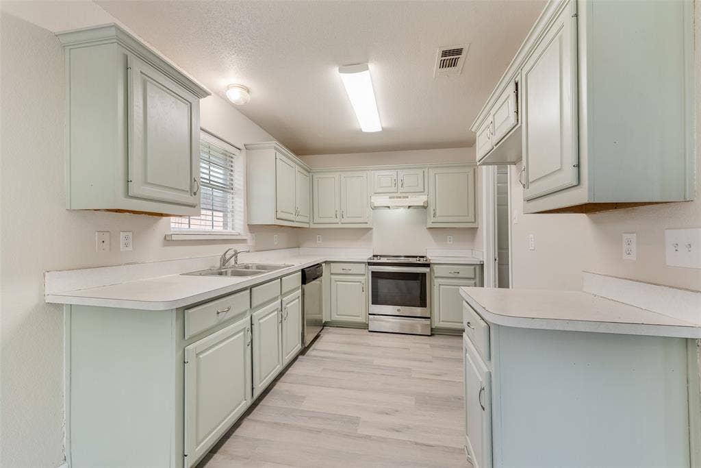 220 Hollywood Drive, Glenn Heights, TX 75154 Kitchen featuring light-toned cabinetry, light-toned countertops, a stainless steel range, and wood-finish flooring