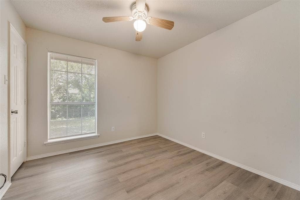 220 Hollywood Drive, Glenn Heights, TX 75154 Wood-finish flooring, single window with blinds, ceiling fan with integrated lighting, and a white paneled door