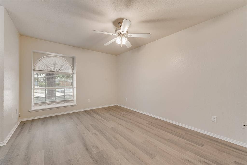 220 Hollywood Drive, Glenn Heights, TX 75154 Arched window with blinds, wood-finish flooring, ceiling fan with light fixture, and neutral wall tones