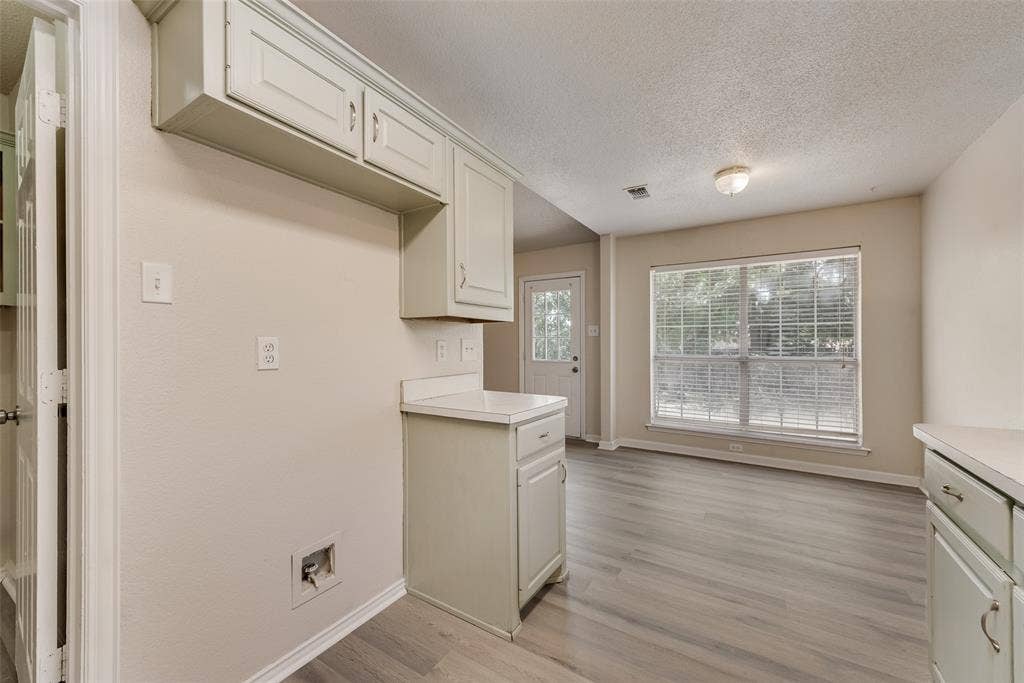 220 Hollywood Drive, Glenn Heights, TX 75154 Light wood-finish flooring, recessed lighting, white cabinetry with silver hardware, white countertops, and a large window with blinds