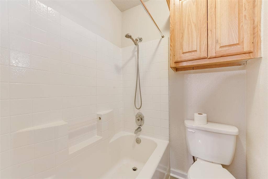 220 Hollywood Drive, Glenn Heights, TX 75154 Bathtub with white tile surround, built-in shelving, and a handheld showerhead