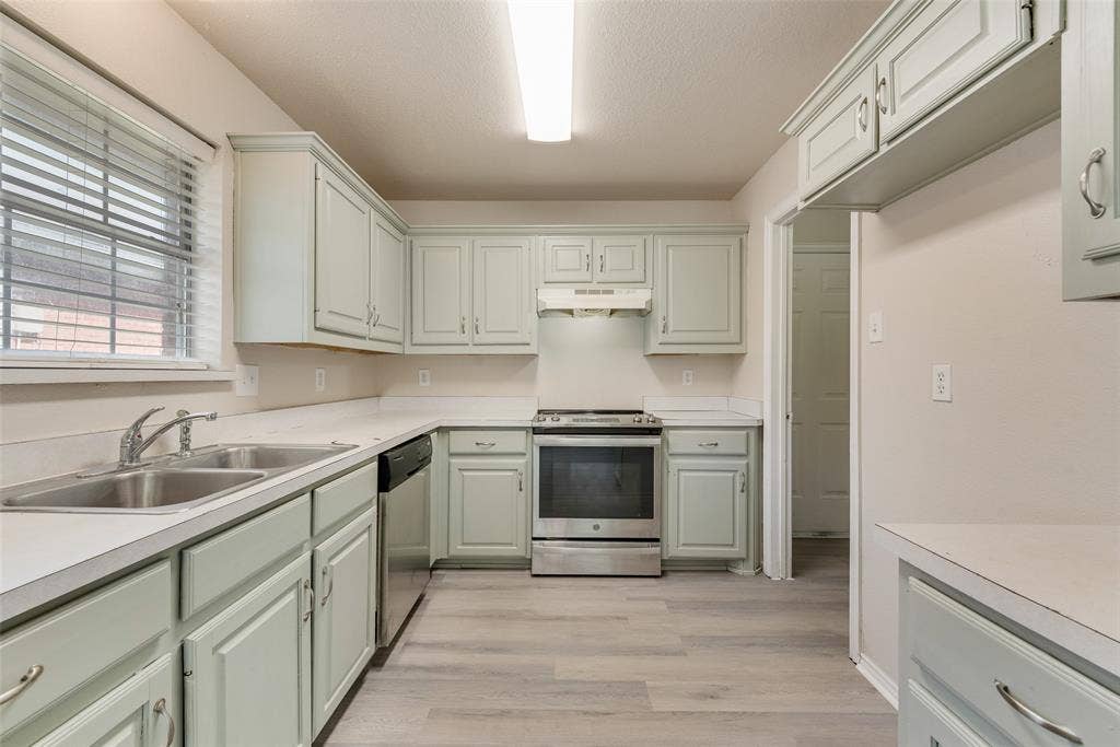 220 Hollywood Drive, Glenn Heights, TX 75154 Kitchen featuring light-colored cabinetry, stainless steel range, and wood-finish flooring