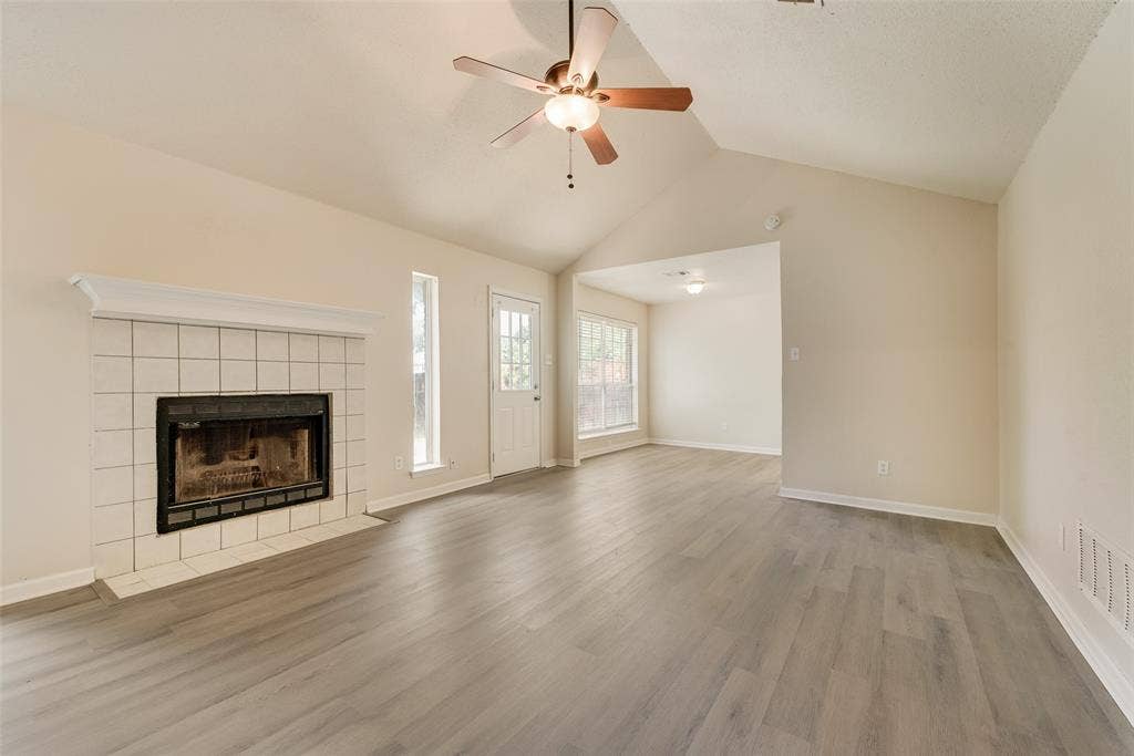 220 Hollywood Drive, Glenn Heights, TX 75154 Vaulted ceiling with an attached ceiling fan, a tiled fireplace, and wood-finish flooring