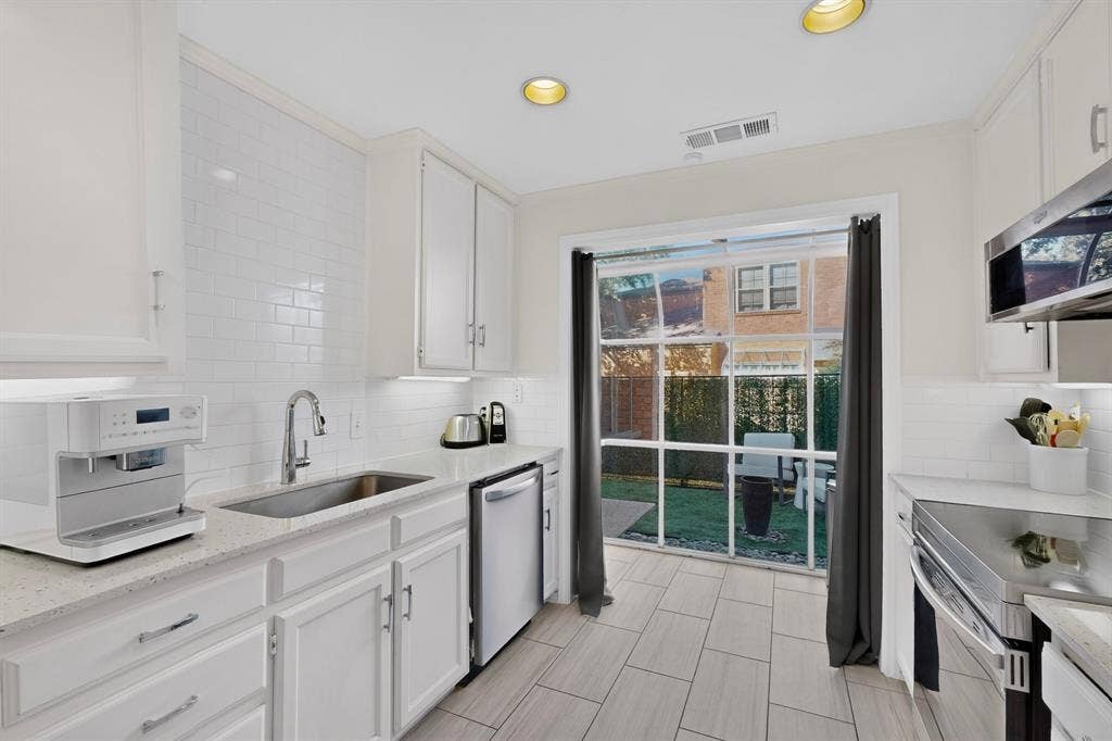 17335 Remington Park Place, Dallas, TX 75252 White cabinetry, subway tile backsplash, stainless steel appliances, recessed lighting, and a sliding glass door to an outdoor space