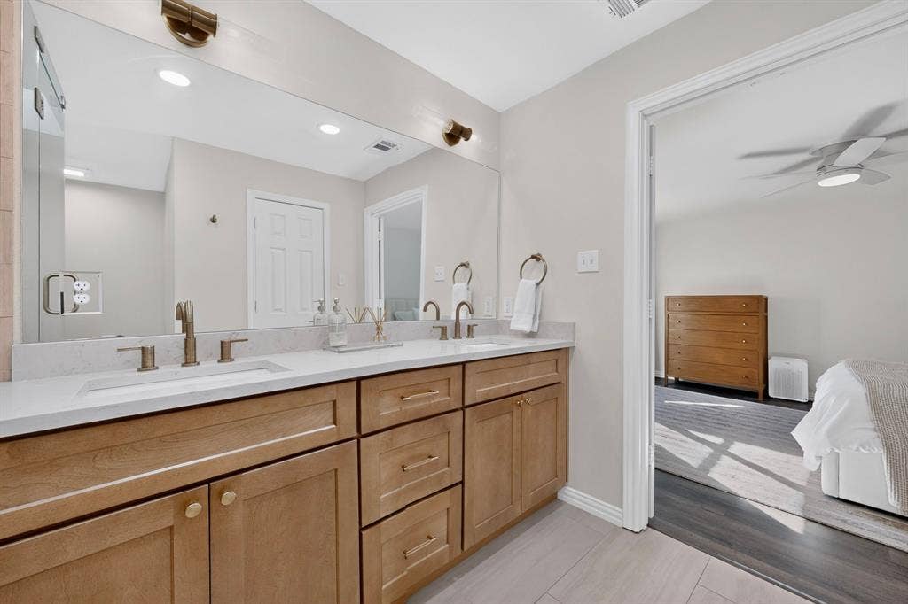 17335 Remington Park Place, Dallas, TX 75252 Dual vanity with light wood-finish cabinetry, white countertops, and bronze-finish fixtures