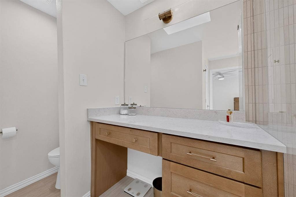 17335 Remington Park Place, Dallas, TX 75252 Vanity with light wood-finish cabinetry, white countertop, and integrated mirror