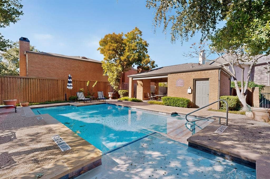 17335 Remington Park Place, Dallas, TX 75252 Community Swimming pool with integrated steps, surrounded by a concrete deck and a brick-clad pool house with an open-air covered patio