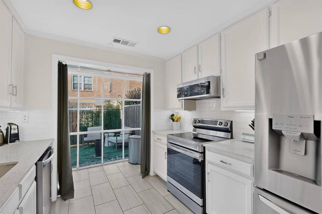 17335 Remington Park Place, Dallas, TX 75252 Kitchen featuring white cabinetry, light-colored countertops, stainless steel appliances, and tile flooring
