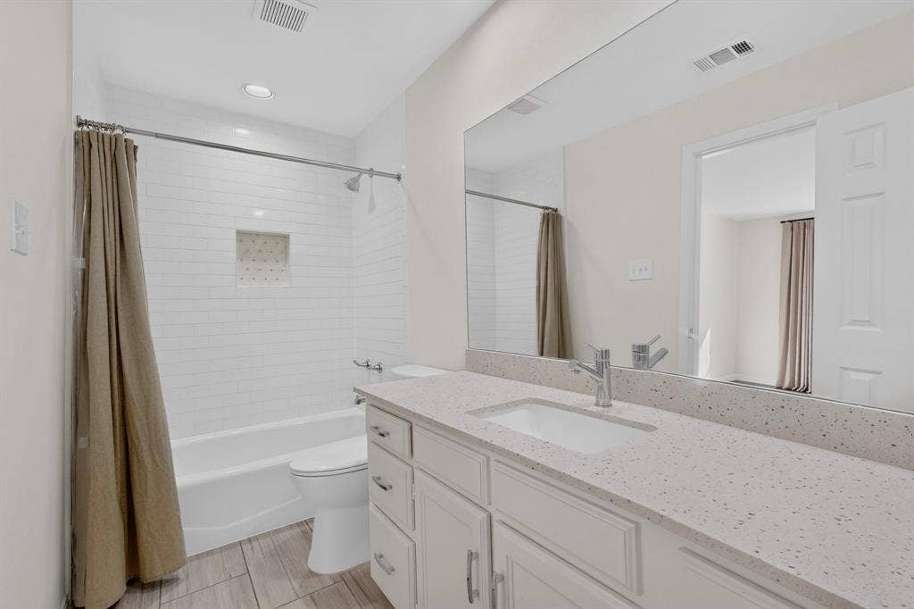 17335 Remington Park Place, Dallas, TX 75252 White subway tile shower surround with integrated niche, polished chrome shower fixtures, and a white bathtub