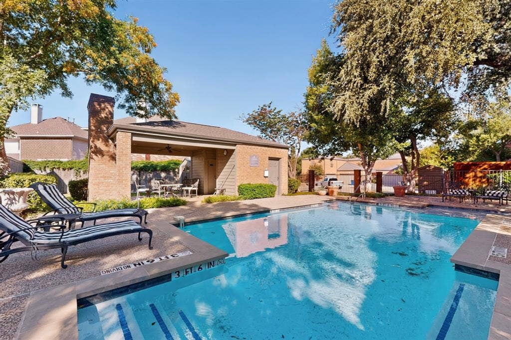 17335 Remington Park Place, Dallas, TX 75252 Community Resort-style pool area featuring a brick-clad covered patio, integrated pool steps, concrete pool deck, and mature trees